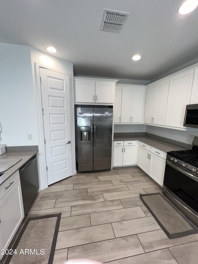 kitchen featuring black appliances, light wood-type flooring, and white cabinets