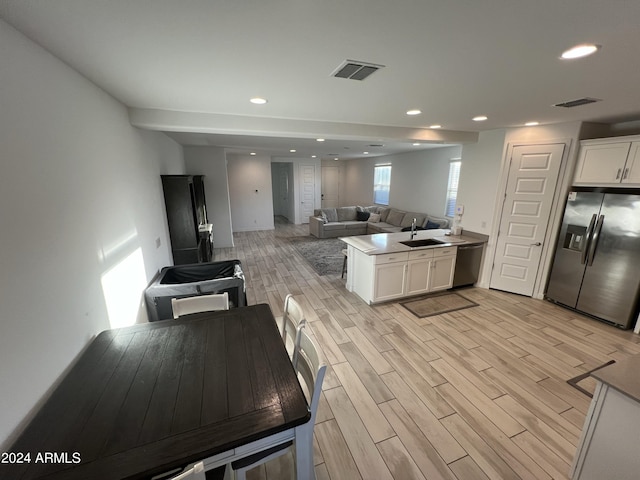 kitchen with appliances with stainless steel finishes, sink, light wood-type flooring, and white cabinets