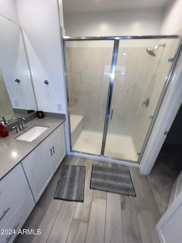 bathroom featuring vanity, hardwood / wood-style flooring, and a shower with shower door