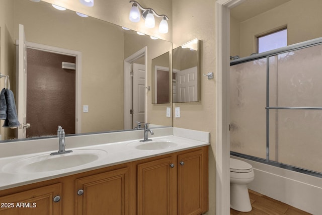 full bathroom featuring vanity, toilet, and bath / shower combo with glass door