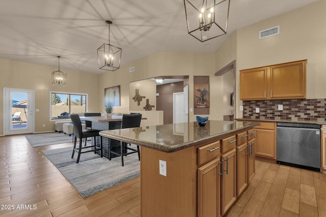 kitchen featuring dishwasher, a center island, dark stone counters, pendant lighting, and light wood-type flooring