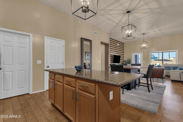 kitchen featuring decorative light fixtures, a center island, and dark stone countertops