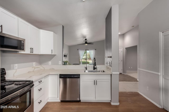 kitchen with appliances with stainless steel finishes, dark wood finished floors, white cabinetry, and a sink