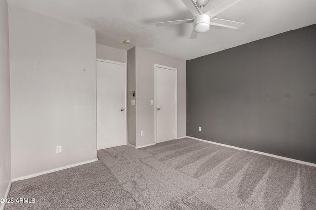 carpeted spare room featuring baseboards and a ceiling fan