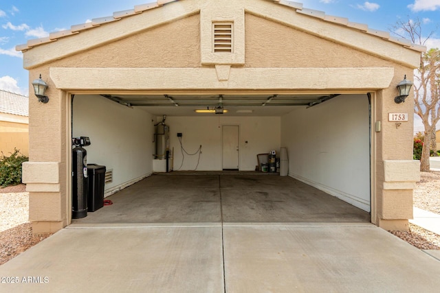 garage with secured water heater and concrete driveway