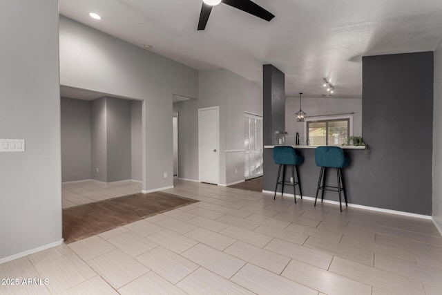 living area with a ceiling fan, wood tiled floor, lofted ceiling, and baseboards