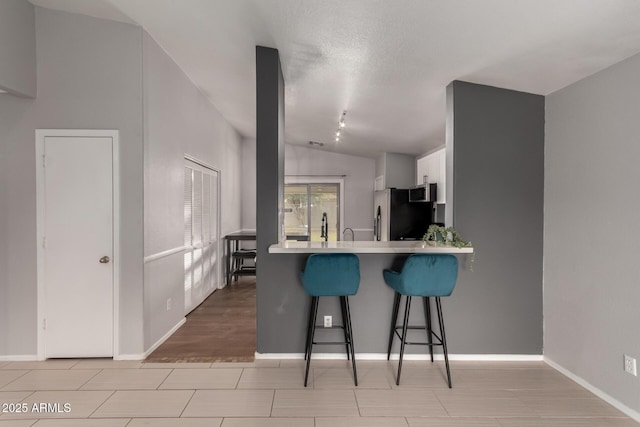 kitchen with white cabinets, appliances with stainless steel finishes, a breakfast bar, a peninsula, and light countertops