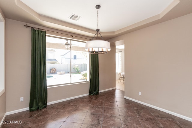 unfurnished dining area featuring a raised ceiling