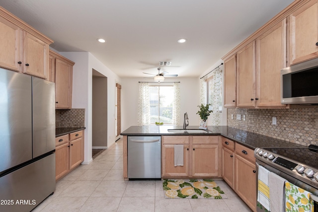 kitchen with stainless steel appliances, sink, dark stone counters, and kitchen peninsula