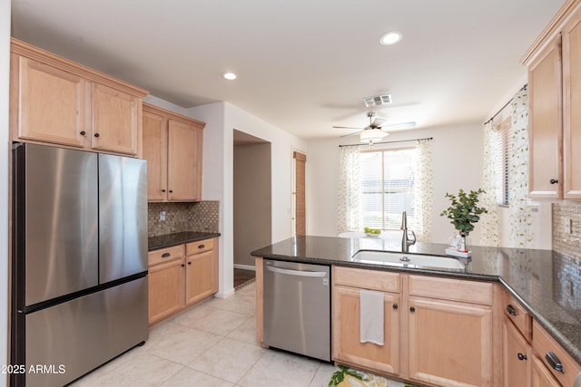 kitchen featuring sink, appliances with stainless steel finishes, tasteful backsplash, kitchen peninsula, and dark stone counters