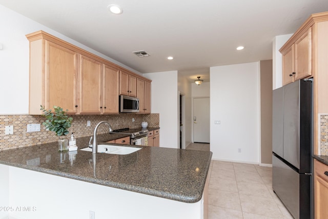 kitchen with tasteful backsplash, sink, dark stone countertops, kitchen peninsula, and stainless steel appliances