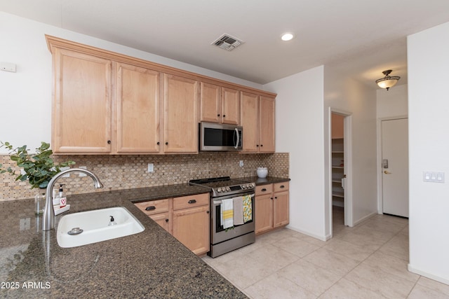 kitchen featuring stainless steel appliances, sink, decorative backsplash, and dark stone countertops