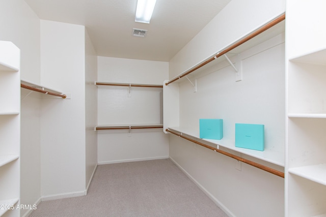 spacious closet with built in desk and light colored carpet