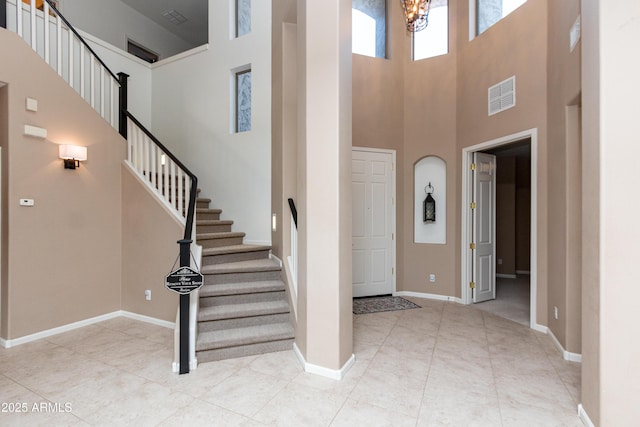 foyer entrance with a notable chandelier, a towering ceiling, and light tile patterned flooring