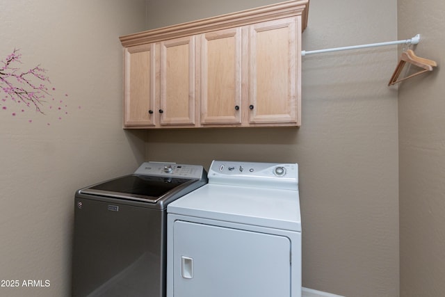 washroom with washer and dryer and cabinets