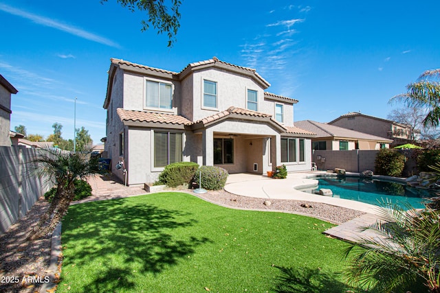 rear view of property featuring a fenced in pool, a patio area, and a lawn