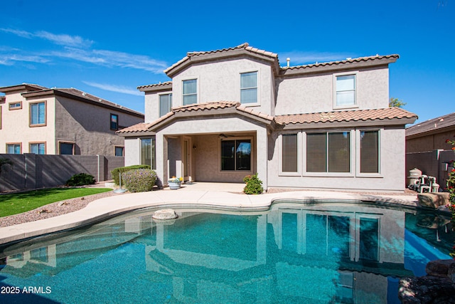 back of property with a fenced in pool