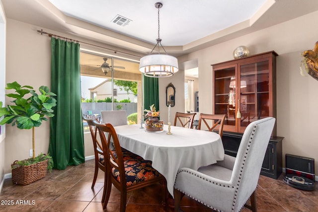 dining room featuring dark tile patterned flooring and a raised ceiling