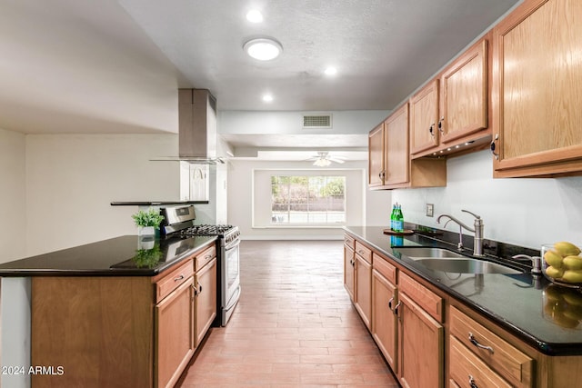 kitchen with stainless steel gas range oven, ceiling fan, sink, light hardwood / wood-style floors, and range hood