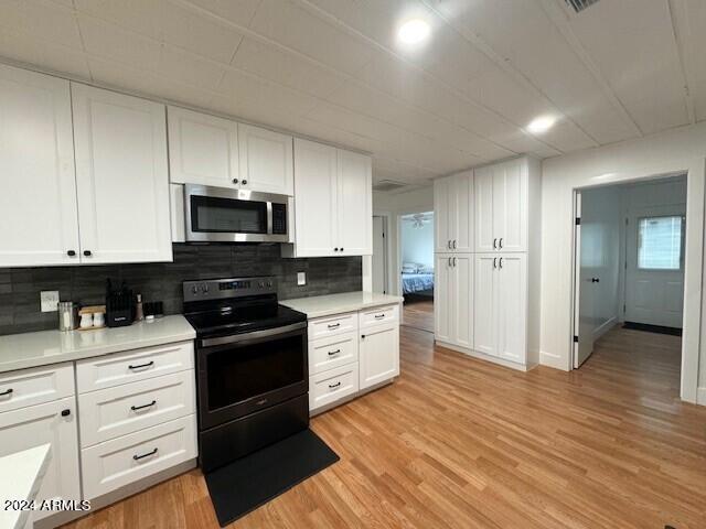 kitchen featuring light hardwood / wood-style flooring, tasteful backsplash, white cabinetry, and electric range oven