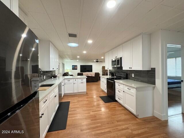 kitchen featuring white cabinets, stainless steel appliances, kitchen peninsula, and light hardwood / wood-style floors