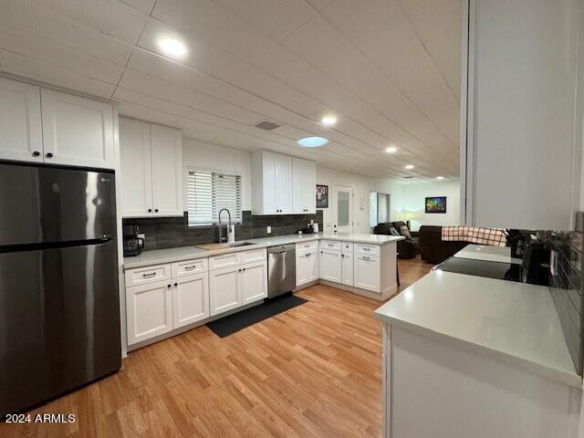 kitchen featuring kitchen peninsula, light hardwood / wood-style flooring, stainless steel appliances, white cabinets, and sink