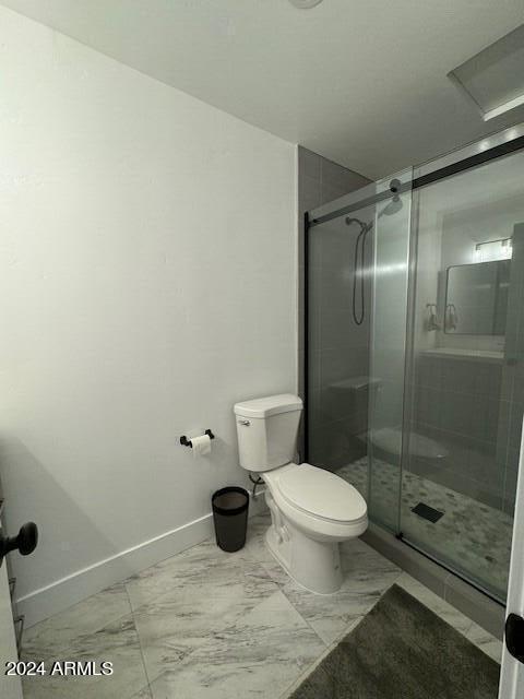 bathroom featuring toilet, tile floors, and a shower with shower door