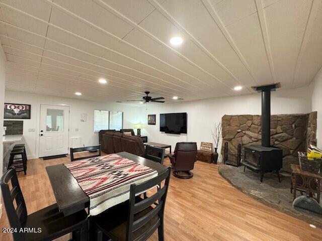 dining area with a wood stove, ceiling fan, and light hardwood / wood-style floors