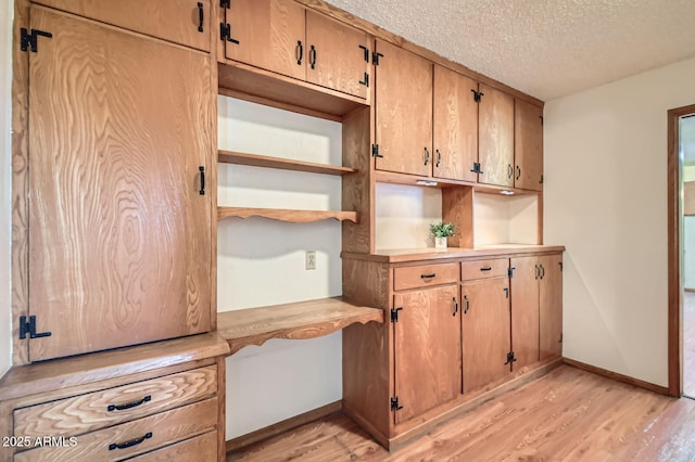 3944 E Oak St, Phoenix, AZ 85008 - kitchen featuring light wood-type flooring, built in desk, open shelves, a textured ceiling, and light countertops