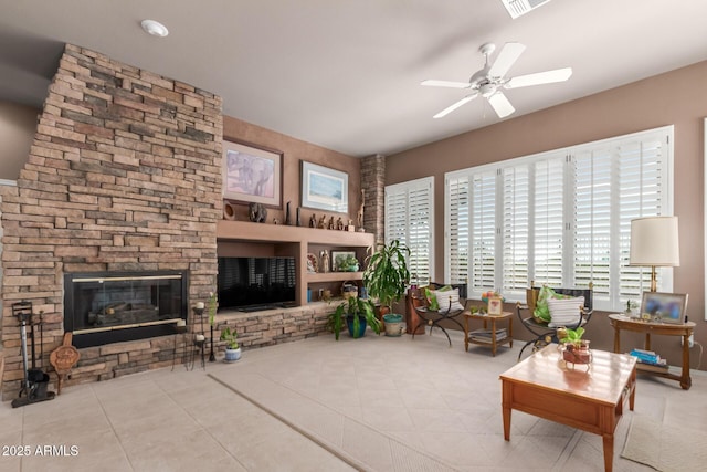 tiled living room with ceiling fan and a fireplace