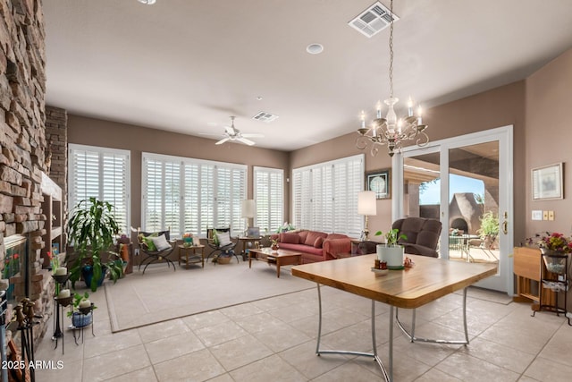 living room with ceiling fan with notable chandelier, a fireplace, and light tile patterned floors