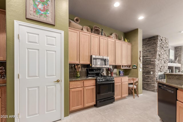 kitchen featuring light brown cabinetry, light tile patterned floors, black appliances, and dark stone counters