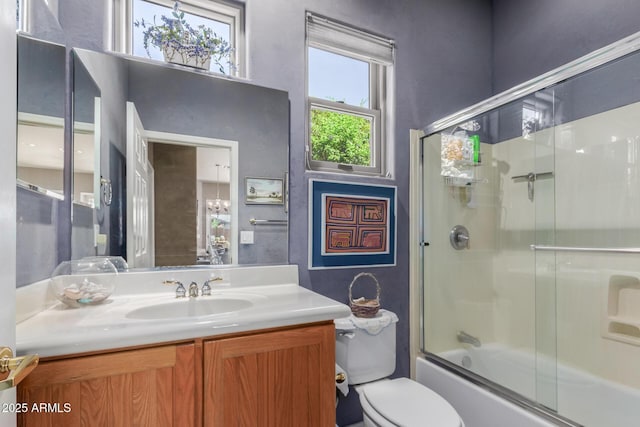 full bathroom featuring vanity, combined bath / shower with glass door, and toilet