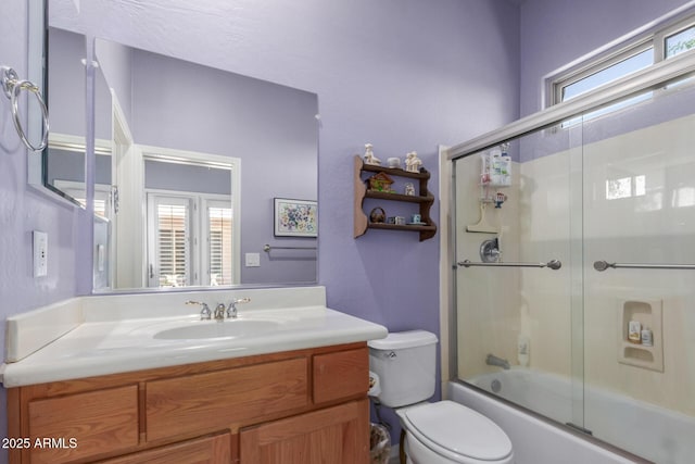 full bathroom with vanity, toilet, and combined bath / shower with glass door