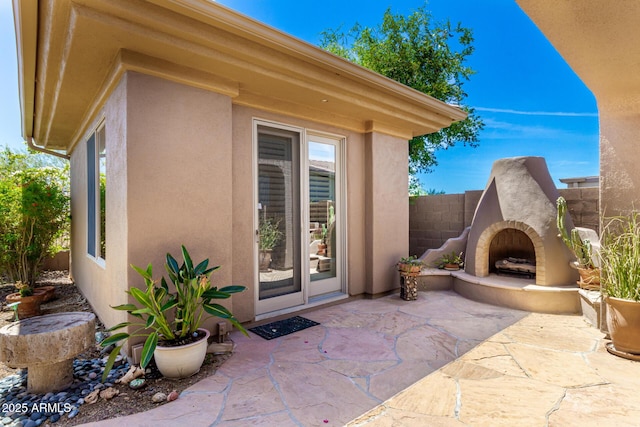 view of patio with fence and exterior fireplace