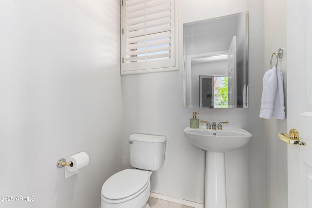 half bathroom with a sink, tile patterned flooring, and toilet