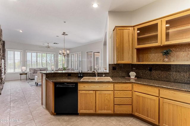 kitchen featuring a sink, black dishwasher, a peninsula, dark stone counters, and decorative backsplash