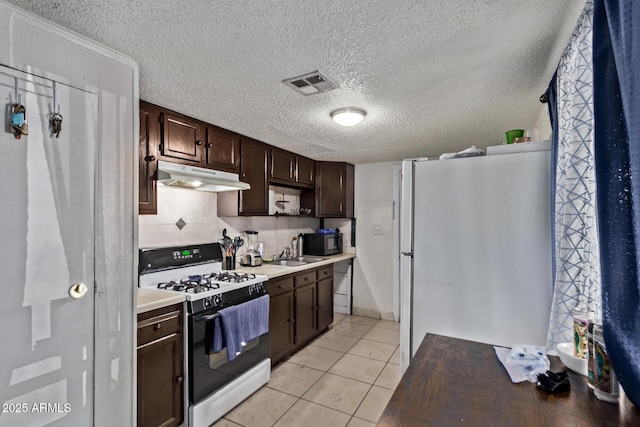 3702 W Sherman St, Phoenix, AZ 85009 - kitchen featuring gas range, freestanding refrigerator, under cabinet range hood, dark brown cabinets, and a sink