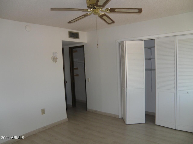 unfurnished bedroom featuring ceiling fan, light hardwood / wood-style floors, a textured ceiling, and a closet