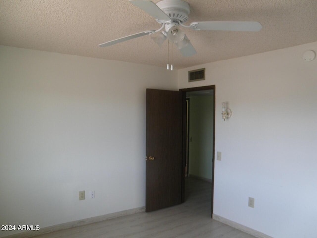 unfurnished room with ceiling fan, light wood-type flooring, and a textured ceiling