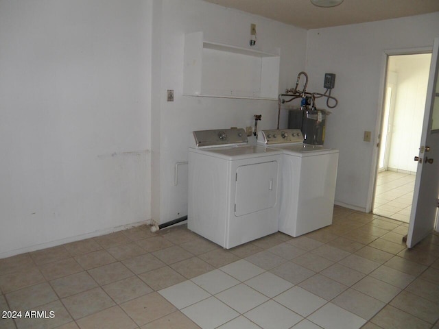 washroom with light tile patterned floors, washer and clothes dryer, and water heater