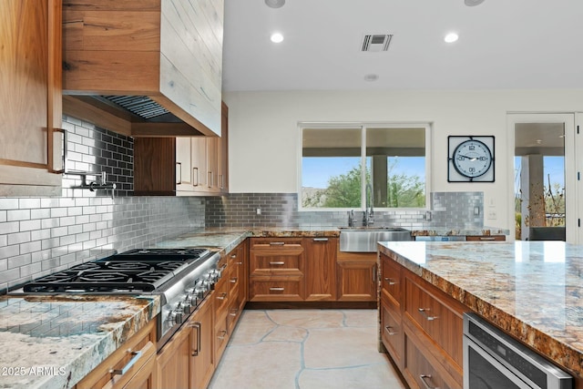 kitchen with light stone counters, a wealth of natural light, sink, and light tile patterned floors