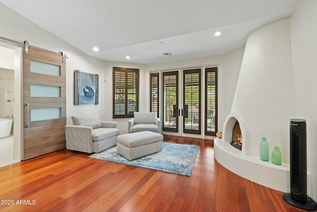 living room with a barn door, hardwood / wood-style floors, and a fireplace