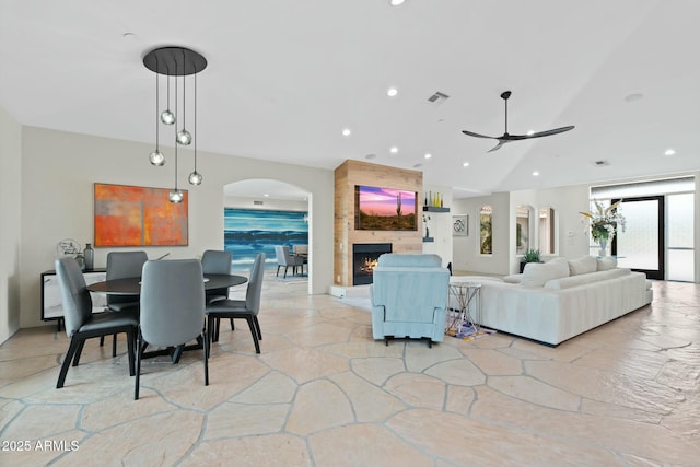 living room featuring ceiling fan, lofted ceiling, and a fireplace