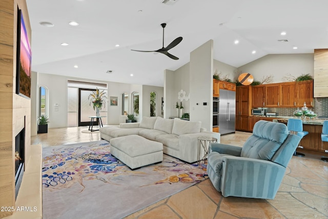 living room with ceiling fan, high vaulted ceiling, and a tile fireplace