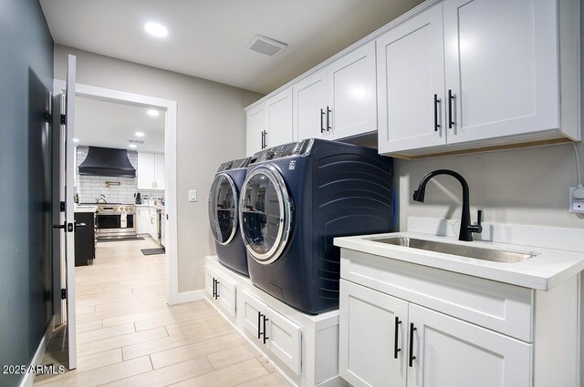 5441 E Wethersfield Rd, Scottsdale, AZ 85254 - laundry room featuring washing machine and dryer, cabinet space, recessed lighting, light wood-style flooring, and baseboards