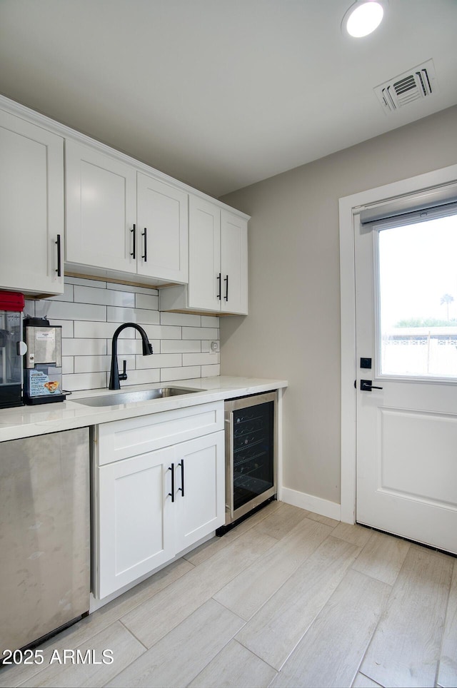 5441 E Wethersfield Rd, Scottsdale, AZ 85254 - kitchen featuring beverage cooler, a sink, decorative backsplash, light countertops, and white cabinetry