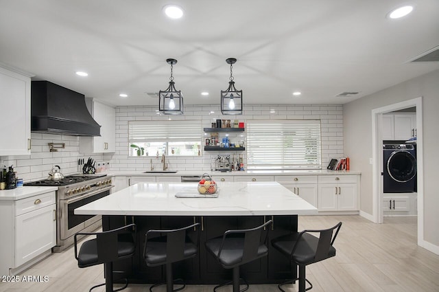 5441 E Wethersfield Rd, Scottsdale, AZ 85254 - kitchen featuring washer / clothes dryer, range with two ovens, premium range hood, decorative backsplash, and recessed lighting
