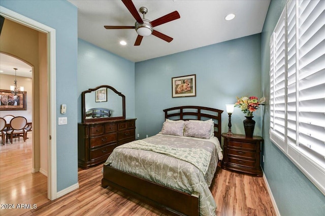 bedroom featuring light hardwood / wood-style floors and ceiling fan with notable chandelier