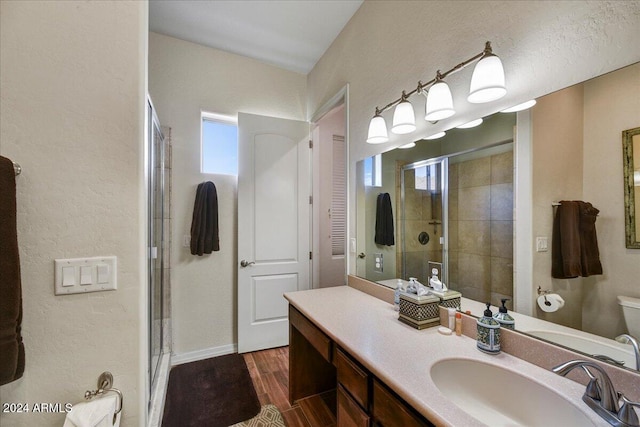 bathroom featuring toilet, a shower with door, vanity, and hardwood / wood-style flooring